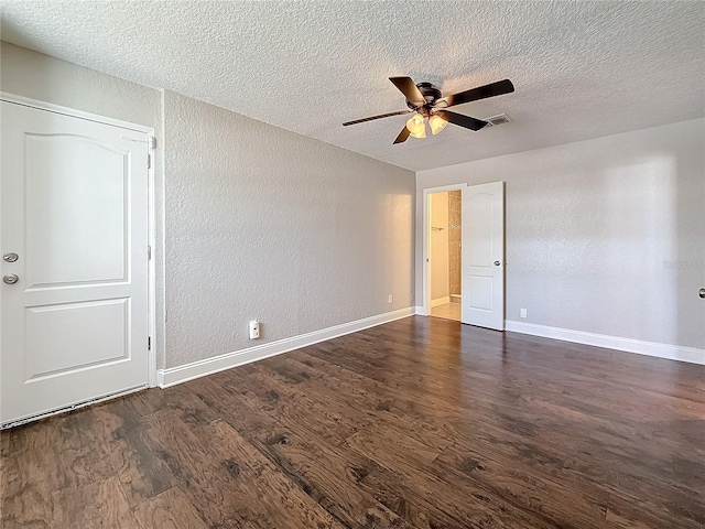 unfurnished room with baseboards, visible vents, and dark wood finished floors