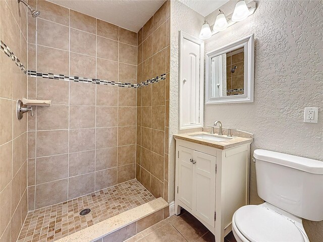 full bath with toilet, a stall shower, a textured wall, and vanity