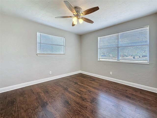 empty room featuring dark wood-style floors, a textured ceiling, and baseboards