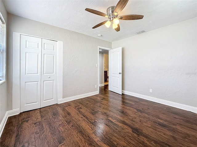 unfurnished bedroom with baseboards, visible vents, dark wood-style flooring, and a textured wall