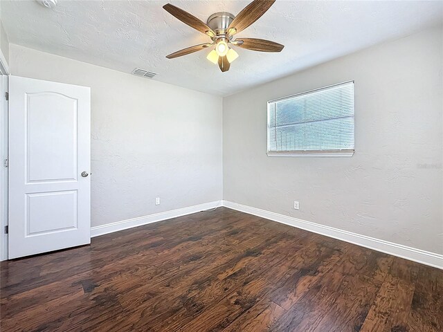 empty room with a textured ceiling, dark wood-style floors, visible vents, and baseboards