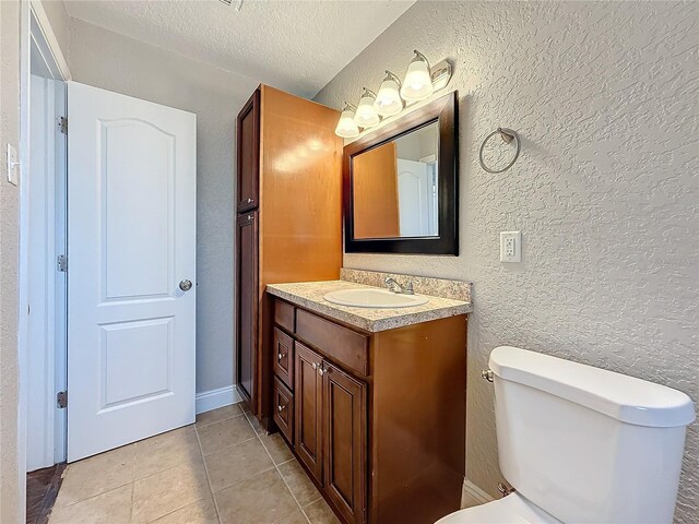 bathroom featuring a textured ceiling, a textured wall, tile patterned flooring, and vanity