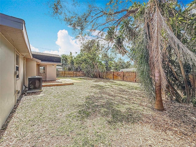 view of yard with central air condition unit, a fenced backyard, and a wooden deck