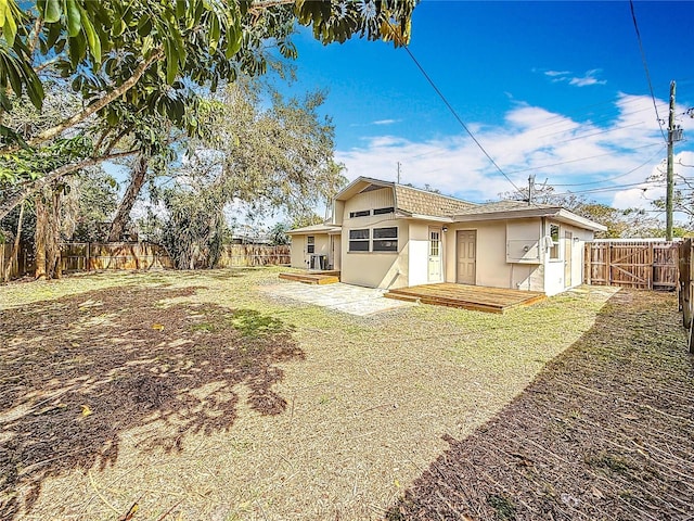 rear view of property with a yard, a fenced backyard, a patio, and stucco siding