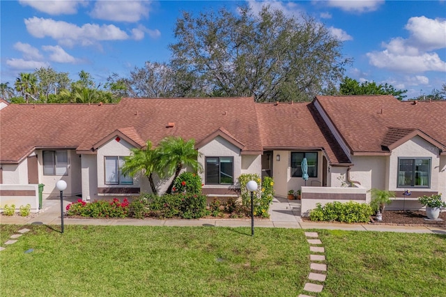 single story home featuring a shingled roof, a front lawn, and stucco siding