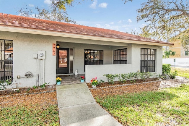 property entrance with covered porch and stucco siding