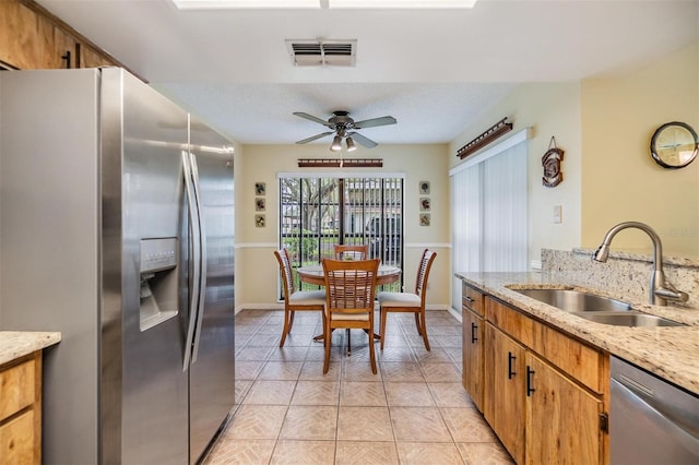 kitchen with light tile patterned floors, visible vents, brown cabinetry, stainless steel appliances, and a sink