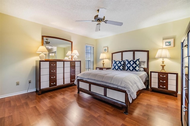 bedroom featuring a textured ceiling, wood finished floors, a ceiling fan, and baseboards