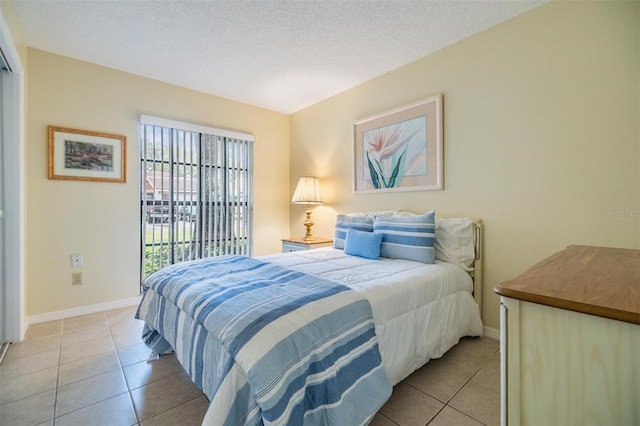 bedroom with a textured ceiling, light tile patterned flooring, and baseboards