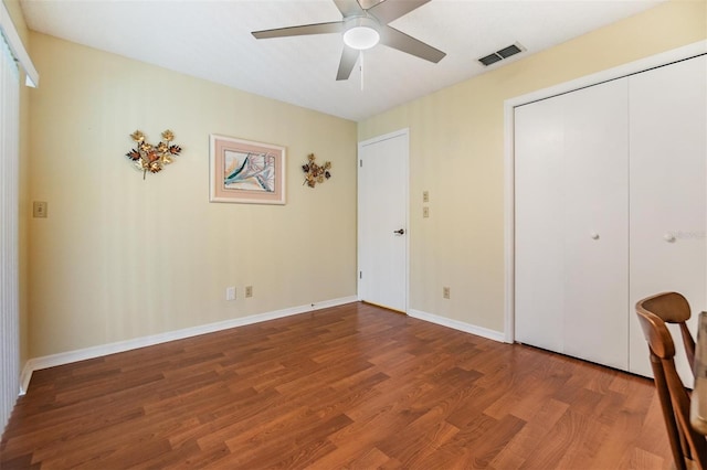 unfurnished bedroom featuring a closet, visible vents, a ceiling fan, wood finished floors, and baseboards