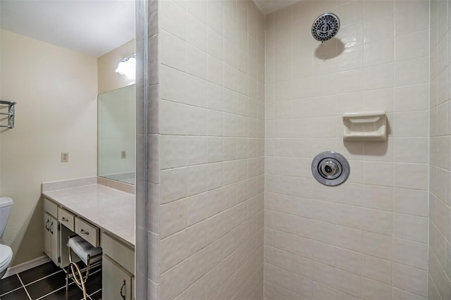 full bathroom with toilet, a tile shower, vanity, baseboards, and tile patterned floors