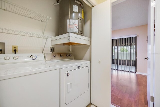 washroom featuring laundry area, baseboards, light wood-style flooring, electric water heater, and separate washer and dryer