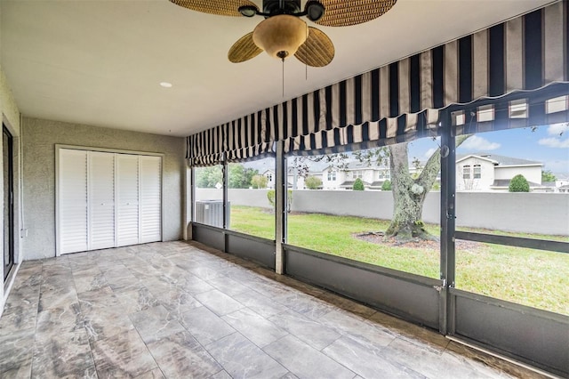 unfurnished sunroom featuring a ceiling fan