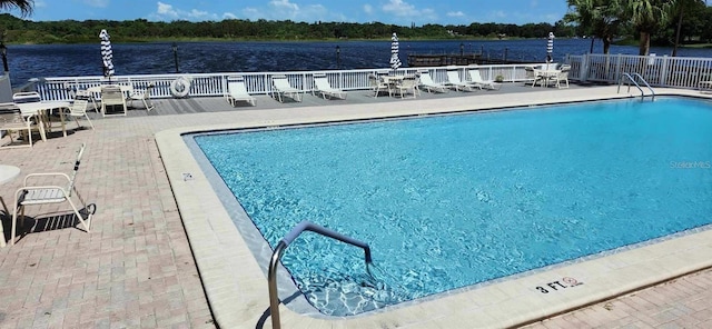 community pool with a patio area and fence