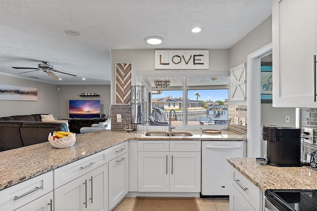 kitchen with dishwasher, light stone counters, open floor plan, white cabinetry, and a sink