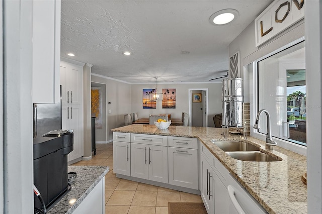 kitchen featuring white cabinets, light stone countertops, pendant lighting, a sink, and light tile patterned flooring