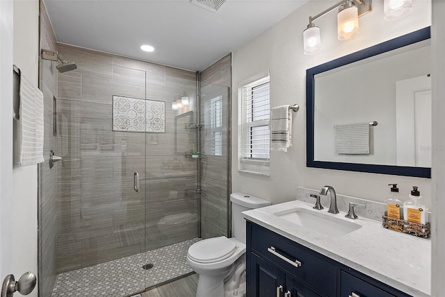 bathroom with toilet, a shower stall, and vanity