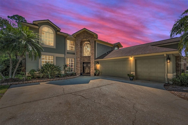 traditional home with a garage, driveway, and stucco siding