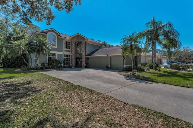 traditional-style home featuring driveway, stone siding, an attached garage, a front yard, and stucco siding