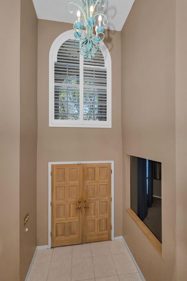 tiled entryway with a chandelier and baseboards