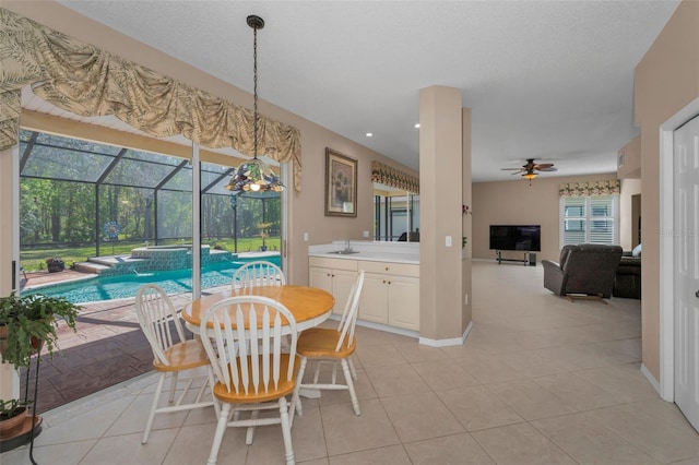 dining room with a healthy amount of sunlight, a sunroom, light tile patterned floors, and a ceiling fan