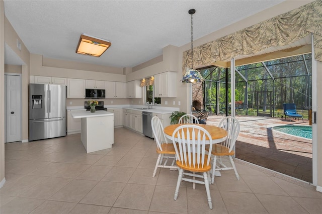 kitchen with light tile patterned floors, white cabinets, light countertops, appliances with stainless steel finishes, and a center island