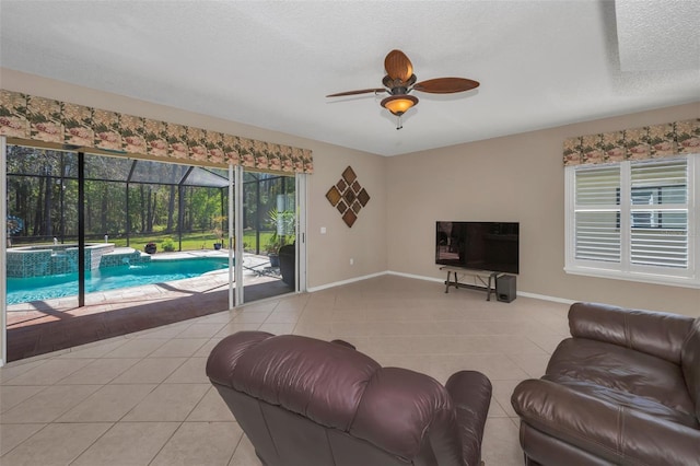 living room with light tile patterned floors, ceiling fan, a textured ceiling, a sunroom, and baseboards