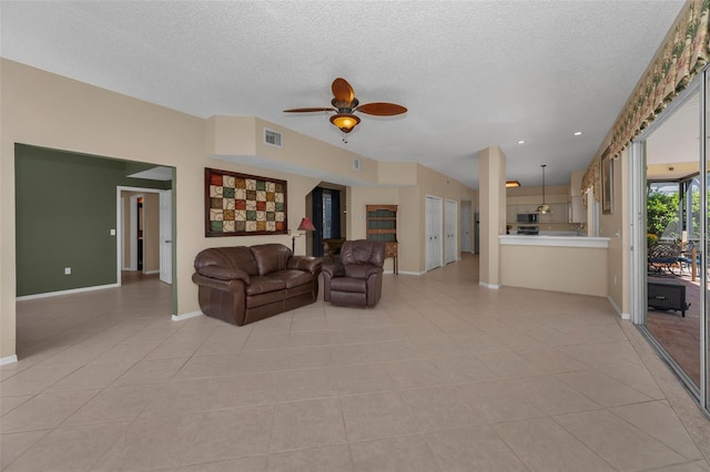 unfurnished living room featuring a ceiling fan, a textured ceiling, and light tile patterned floors