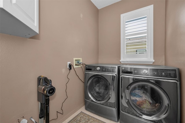 clothes washing area with washing machine and dryer, tile patterned flooring, and cabinet space