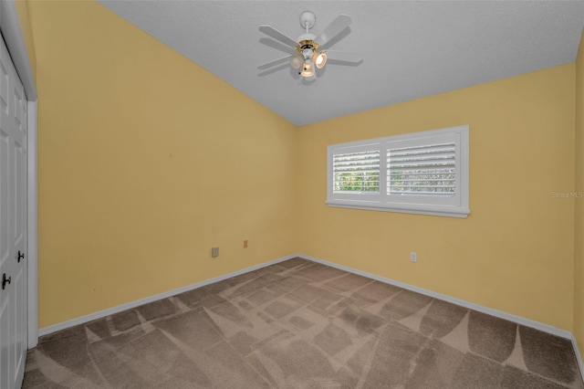 empty room featuring carpet floors, vaulted ceiling, baseboards, and a ceiling fan