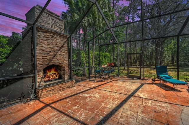 patio terrace at dusk with an outdoor stone fireplace and a lanai