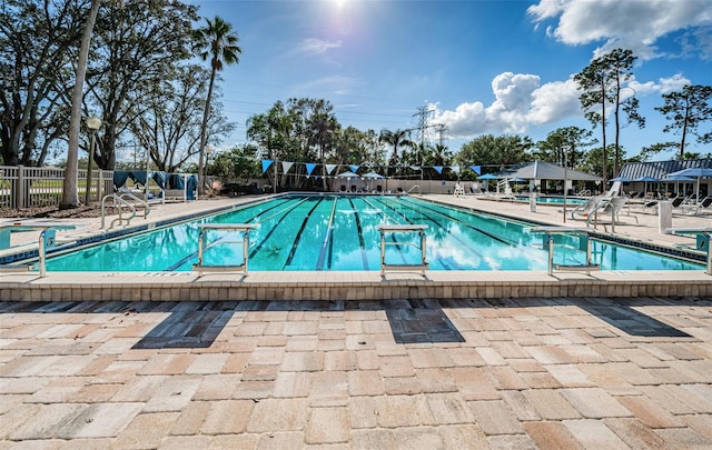 community pool with fence and a patio