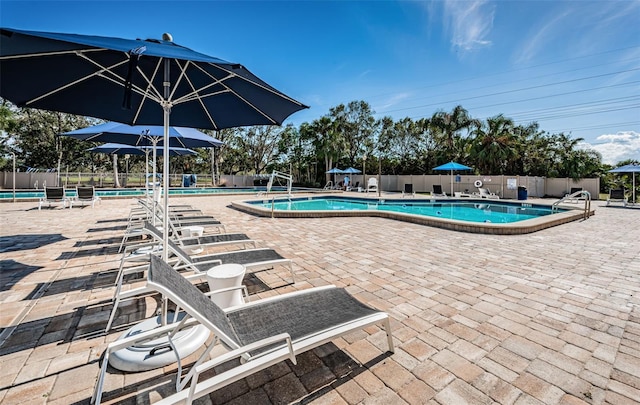 pool with a patio and fence