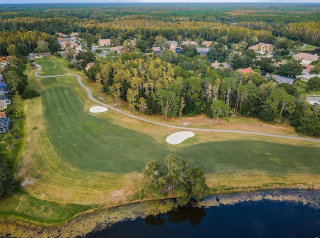 drone / aerial view with a water view, golf course view, and a view of trees