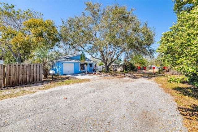 view of front facade featuring an attached garage, driveway, and fence