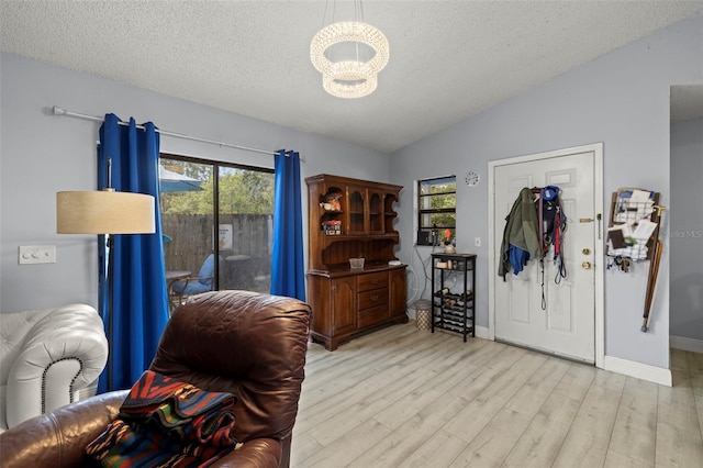 office space featuring baseboards, lofted ceiling, a textured ceiling, light wood-type flooring, and a chandelier