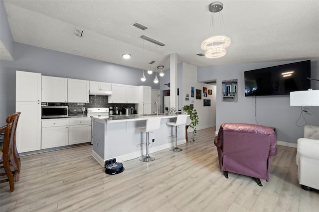 kitchen featuring open floor plan, white cabinets, and hanging light fixtures