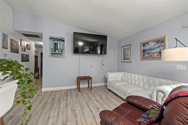 living area with a textured ceiling, light wood-style flooring, visible vents, baseboards, and vaulted ceiling