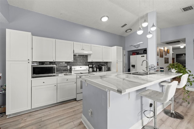 kitchen featuring white appliances, visible vents, under cabinet range hood, and white cabinetry