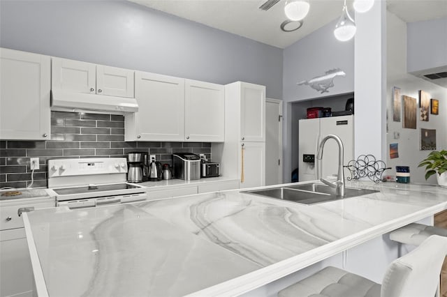 kitchen featuring light stone counters, under cabinet range hood, white appliances, white cabinets, and a kitchen bar