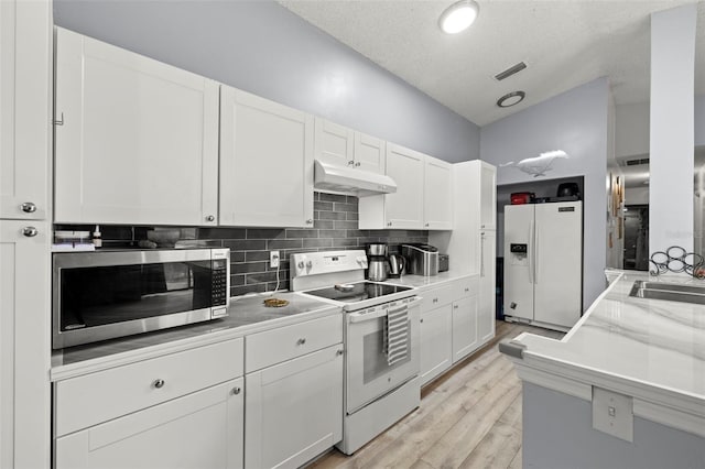 kitchen with visible vents, white appliances, white cabinets, and under cabinet range hood