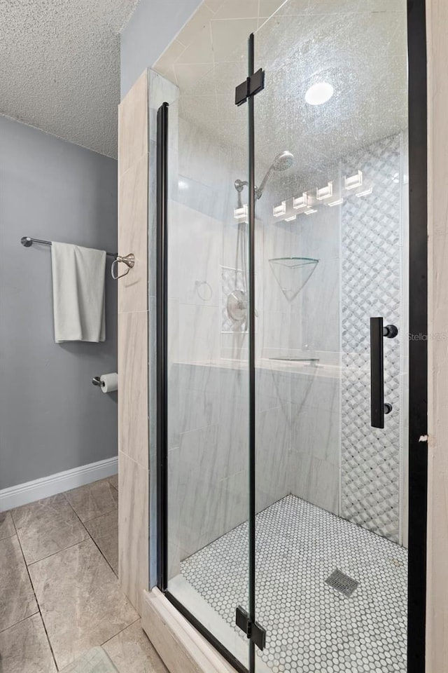 full bathroom with tile patterned flooring, baseboards, a shower stall, and a textured ceiling