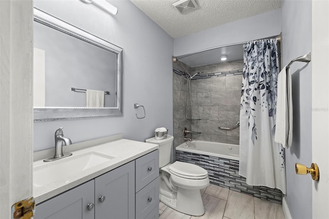 bathroom featuring a textured ceiling, toilet, vanity, visible vents, and tiled shower / bath