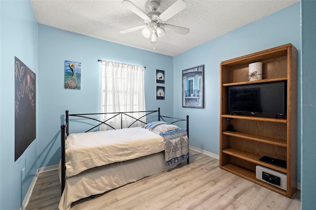 bedroom with baseboards, ceiling fan, light wood-style flooring, and a textured ceiling