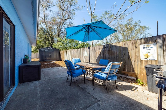 view of patio / terrace with an outbuilding, a shed, outdoor dining area, and a fenced backyard