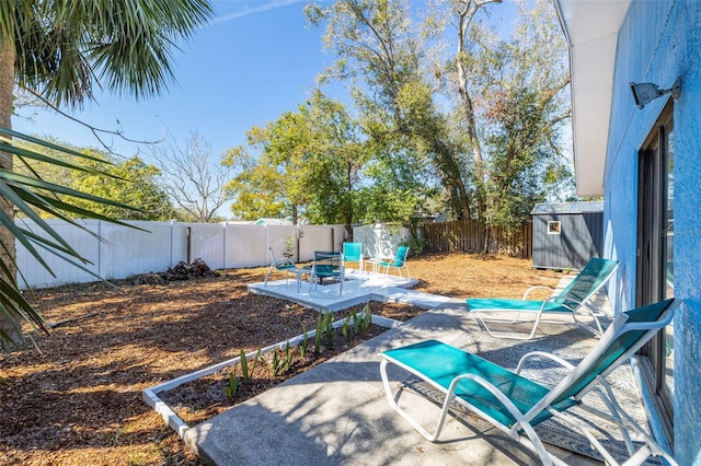 view of patio / terrace with an outbuilding, a storage unit, and a fenced backyard