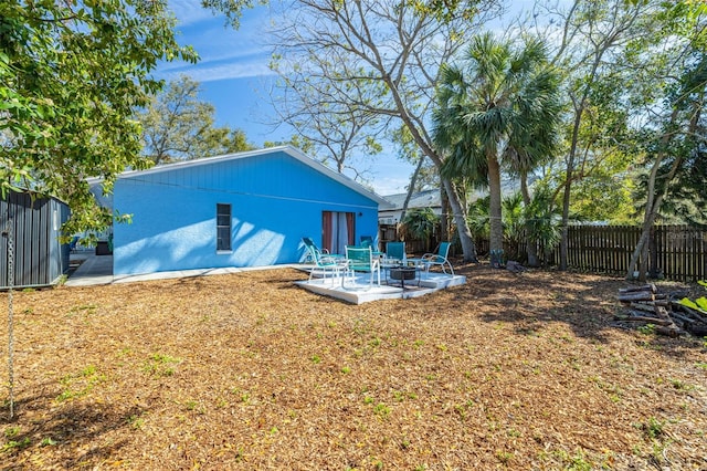 rear view of property with a patio, an outdoor fire pit, a lawn, and a fenced backyard