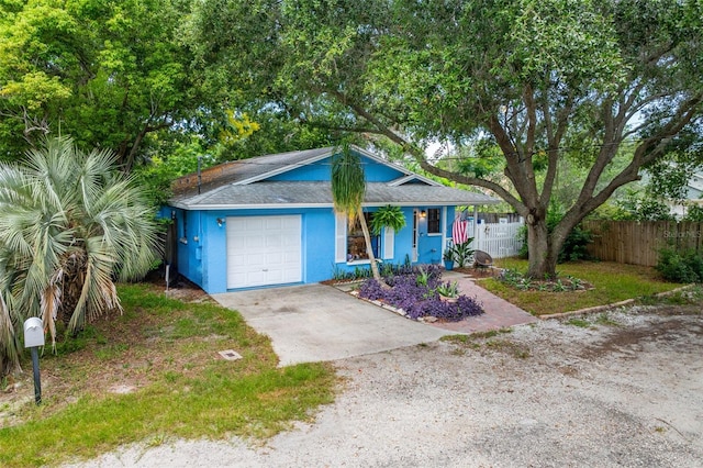 view of front facade with driveway, a garage, and fence