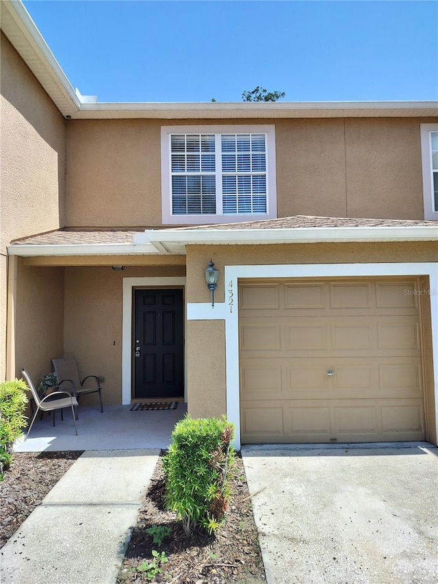 property entrance with concrete driveway, an attached garage, and stucco siding