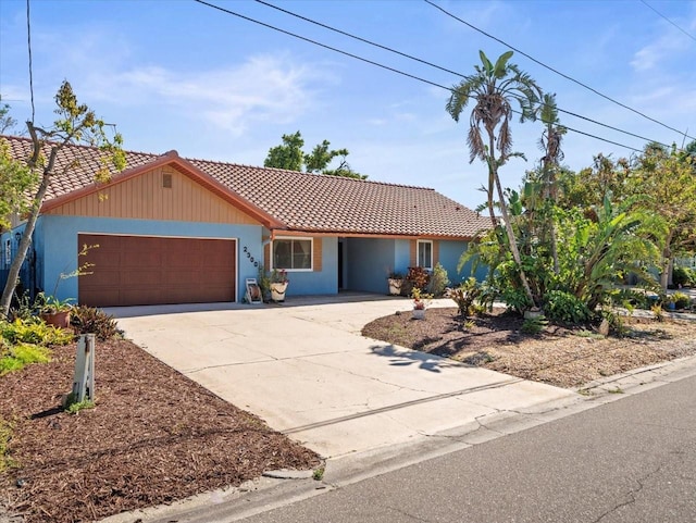 ranch-style home with driveway, a tiled roof, and an attached garage